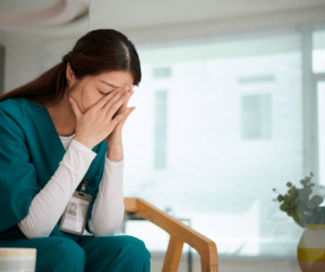 Nursing burnout in hospital setting image of burned out nurse with head in her hands
